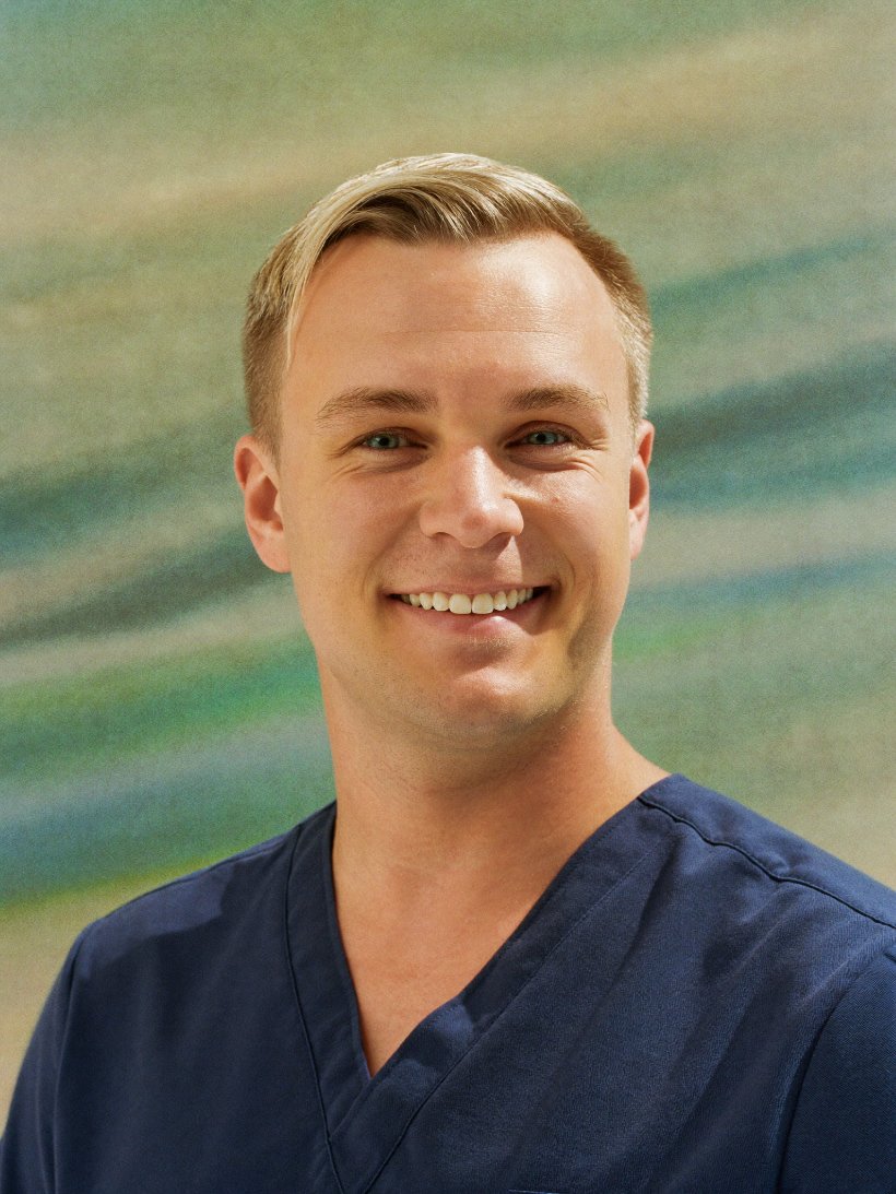 Portrait of a smiling care worker in navy scrubs.