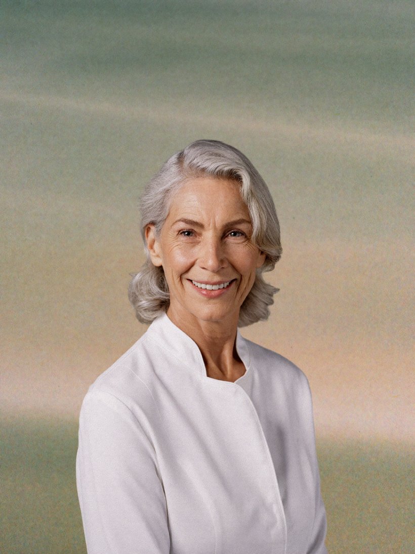 Portrait of a smiling senior clinician in a white coat.