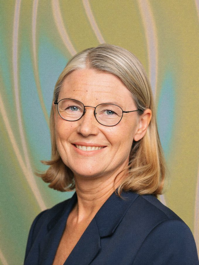 Portrait of a smiling compliance officer with glasses in a navy blazer.