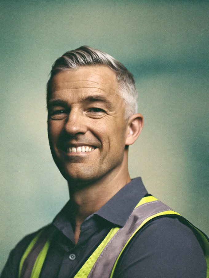 Portrait of a smiling EHS officer in a high-visibility safety vest.
