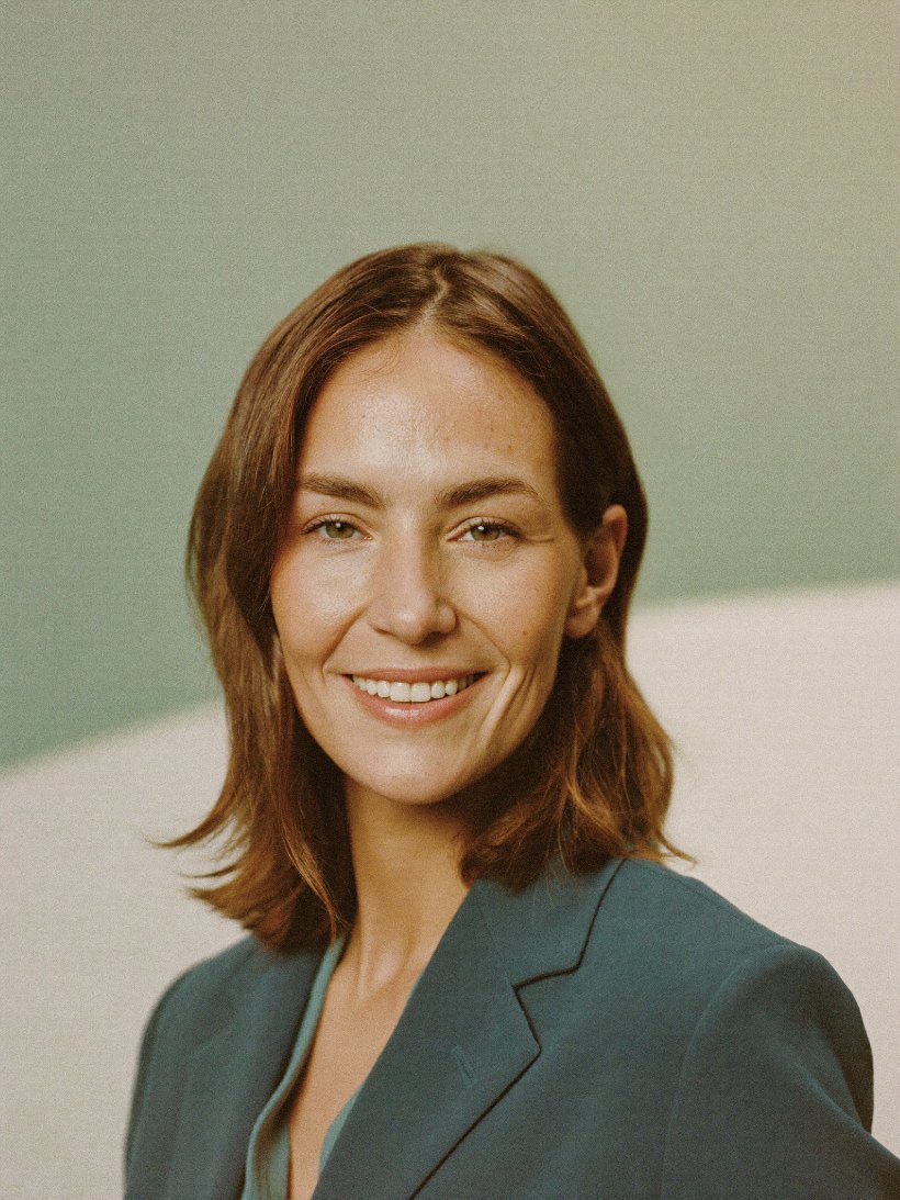 Portrait of a smiling operations manager in a teal blazer.